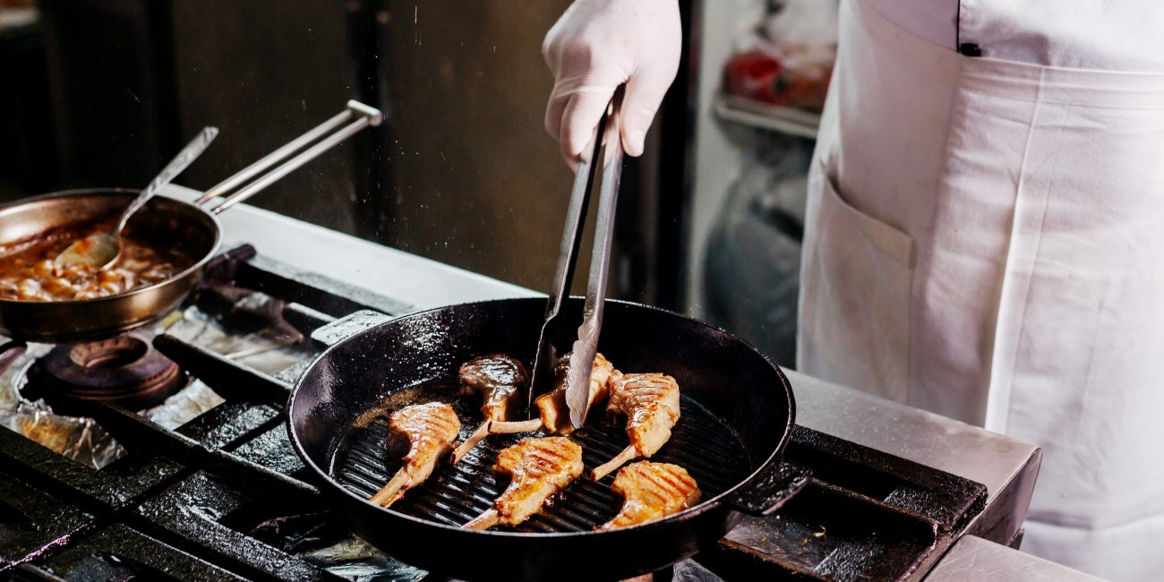 cocine-preparando-costillas-de-carne-dentro-de-una-sarten-de-metal-negro-en-la-cocina